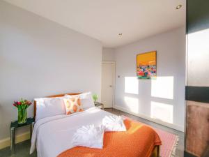 ein Schlafzimmer mit einem weißen Bett und einem orangefarbenen Ottomanen in der Unterkunft Apt w Garden Oasis in Finchley in Hendon