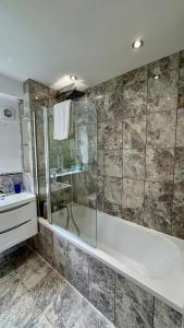a bathroom with a shower and a tub and a sink at 3-bed London apt w free parking in Ealing +13 photos