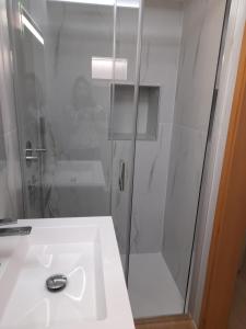 a bathroom with a shower and a white sink at Chalé da Fonte - T2 in Geres