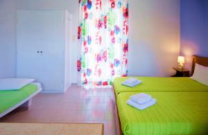 a small room with two beds and a green bedspread at Stefanie Studios in Egina