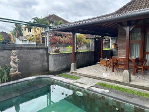 a house with a swimming pool in front of a house at Ketut's Place Penestanan Ubud in Ubud