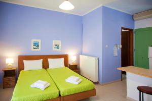 a bedroom with a green bed and blue walls at Stefanie Studios in Egina