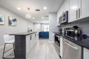 Modern 2BR DownTown Home with King Bed, Long Stays, WiFi, Netflix في أورلاندو: مطبخ بخزائن بيضاء وطاولة عمل سوداء