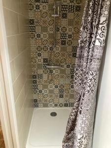 a shower with a black and white shower curtain at Le Clos qui Clôt in Le Fenouiller