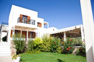 a white house with flowers in the yard at Villa Christine in Agia Anna Naxos