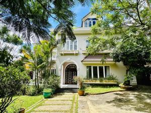 a white house with trees in front of it at Jakaranda Villa Dalat in Da Lat