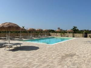 a swimming pool with chairs and umbrellas at Tenuta Corano Nardò in Nardò