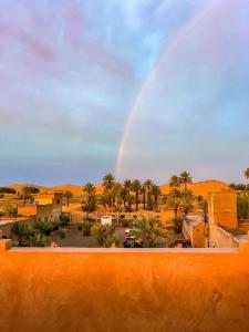 a rainbow in the desert with a parking lot at Hotel Riad Le Petit Prince in Merzouga