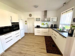 a kitchen with white cabinets and black counter tops at Villa Weißer Schwan in Trent