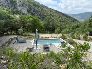 - une piscine avec une chaise et un parasol dans l'établissement Gites Les Rochers de Plaisians, à Plaisians