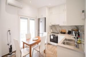 a kitchen with white cabinets and a wooden table with chairs at Kyra's Luxury Suites 3 in Chios