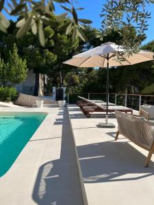 a pool with an umbrella and chairs and a table and an umbrella at seaview apartment - villa a’more in Milna