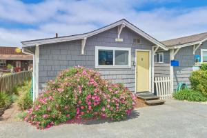 a gray house with a yellow door and a bush of flowers at The Nest #8 in Long Beach +12 photos