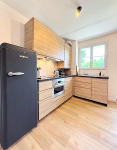 eine Küche mit einem schwarzen Kühlschrank und Holzschränken in der Unterkunft Le Genêt Disney 15min Train 8min Paris Parking in Bussy-Saint-Georges + 19 Fotos