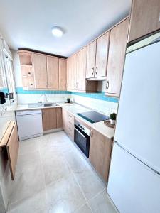 een keuken met houten kasten en een witte koelkast bij Apartamento Empul Rota Príncipe in Rota