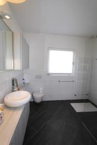 un bagno bianco con lavandino e WC di Casa Ermenegilda, 4,5-Zimmerhaus by HolAp SA ad Ascona