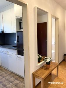 een keuken met witte kasten, een tafel en een spiegel bij Residenza Sabrina 10 by Fewotessin in Ascona +15 foto's