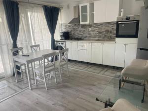 eine Küche mit weißen Schränken und einem Tisch und Stühlen in der Unterkunft Ayan&Anto YSY Apartament in Eforie Nord