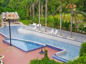 a swimming pool with white chairs and a fountain at Phuiyara Resort in Nakhon Nayok