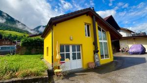 RechyCharmante maisonnette avec jardin的一栋黄色的房子，有白色的门和一些椅子