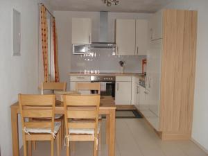 una cocina con mesa de madera y sillas. en Ferienwohnungen Simon - Hauserhof, en Oberperfuss