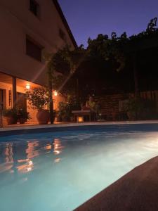 a swimming pool at night with a person sitting at a table at Hanami House Boutique 4 Estrellas Valle del Jerte in Navaconcejo +39 photos