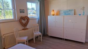 a bedroom with a white dresser and two chairs at Chalet Flandesbach in Velbert