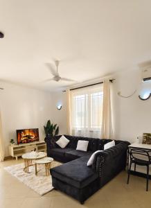 a living room with a black couch and a fireplace at Ronny Homes in Mombasa
