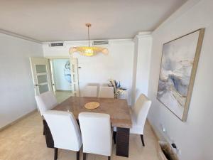 a dining room with a table and white chairs at Los Flamingos Villa Padierna Apartment in Estepona