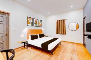 a bedroom with a bed and a table and a tv at Townhouse Oak Puducherry Airport in Puducherry