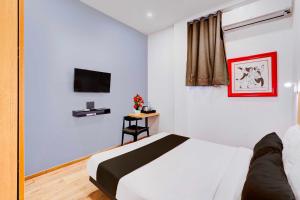 a white bedroom with a bed and a tv at Townhouse Oak Puducherry Airport in Puducherry +30 photos