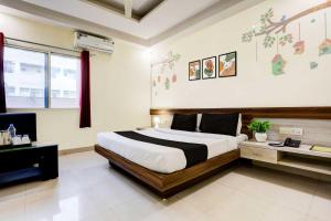 a bedroom with a large bed and a desk at Townhouse Oak Hoshangabad Capital Mall in Bhopal