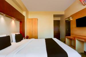 a bedroom with a large white bed with a flat screen tv at Townhouse Oak Udaipur City Railway Junction in Udaipur +19 photos