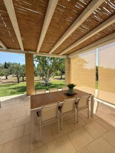 een patio met een houten tafel en stoelen bij Villa Malepè con piscina in Torre dell'Orso
