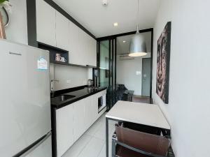 a kitchen with white cabinets and a table and a refrigerator at The Base Central Pattaya by WWC in Pattaya Central
