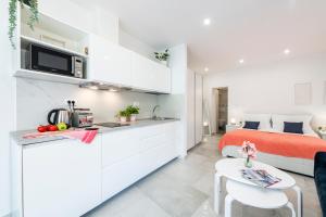 a white kitchen and bedroom with a bed and a table at Stylish sea view studio in Dubrovnik