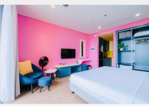 a bedroom with a white bed and a pink wall at FLAMINGO Ibiza HaiTien - Ivy Abtel in Thanh Hóa