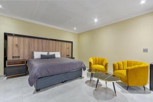 a bedroom with a bed and two yellow chairs at QUEEN GUEST Villa in Germiston