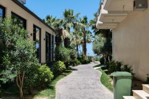 a walkway between two buildings with palm trees at Roses Apartment in Golem