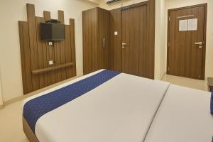 a bedroom with a bed with wooden cabinets and a tv at StayGuru Hotel Atithi in Bhuj