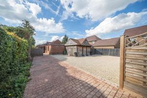 ein Haus mit einer gemauerten Auffahrt und einem Holzzaun in der Unterkunft 8 Bedroom, 6 Bath House, Large Patio, Large Parking in Hardwicke