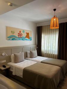 a hotel room with two beds and a chandelier at Hotel Gumusluk in Gumusluk