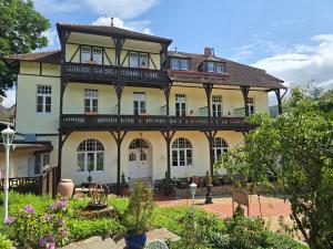 a large yellow house with a balcony on top at PARK VILLA zentral am Mittelrhein Zimmer&Apartments Self check in Aparthotel in Boppard