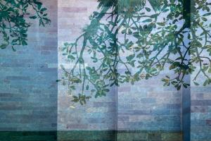 a tree branch with leaves in front of a brick wall at Blossom Eco Luxe Villas by Ekosistem in Canggu