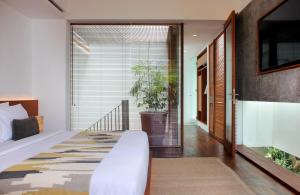 a bedroom with a bed and a large window at Blossom Eco Luxe Villas by Ekosistem in Canggu