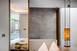 a bedroom with a tub and a bed and a mirror at Blossom Eco Luxe Villas by Ekosistem in Canggu