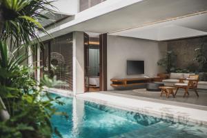a house with a swimming pool and a living room at Blossom Eco Luxe Villas by Ekosistem in Canggu