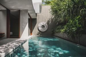 a swimming pool next to a house with plants at Blossom Eco Luxe Villas by Ekosistem in Canggu