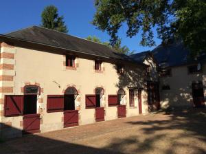a large white building with red doors and windows at La Sellerie in Cour-Cheverny