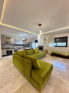 a living room with two green couches and a kitchen at Logement luxueux avec 2 piscines in Dar Hamida
